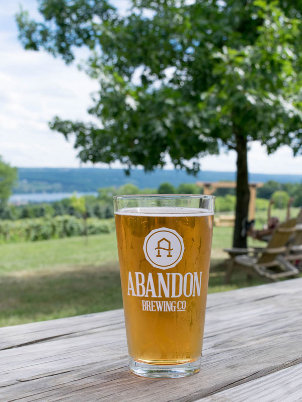 Full pint glass on picnic table with Keuka Lake in background